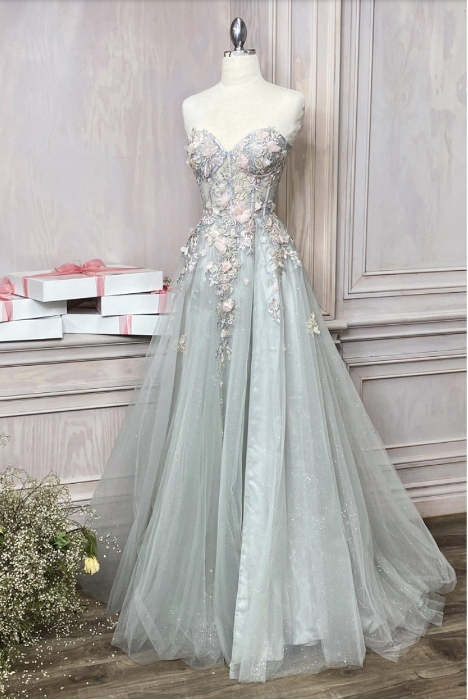 Strapless ball gown by Andrea & Leo, style A1089. Features intricate and delicate details with sheer floral appliqué corset bodice, leg slit, and over skirt. Available in Sage, Paris-Blue, and Blush-Mauve colors.