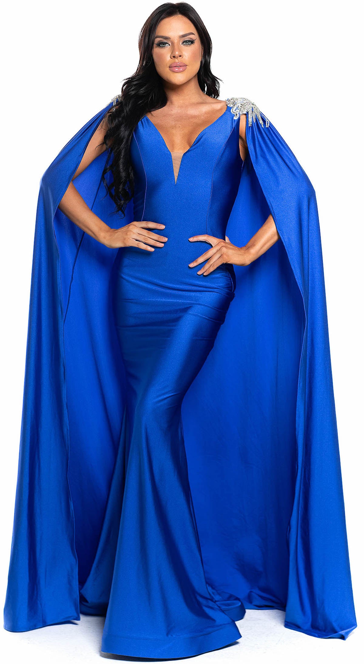 Jessica Angel 896 Jersey Gown in royal blue with embellished shoulders, a deep V-neckline, and a floor-length cape. Ideal for prom and formal events.