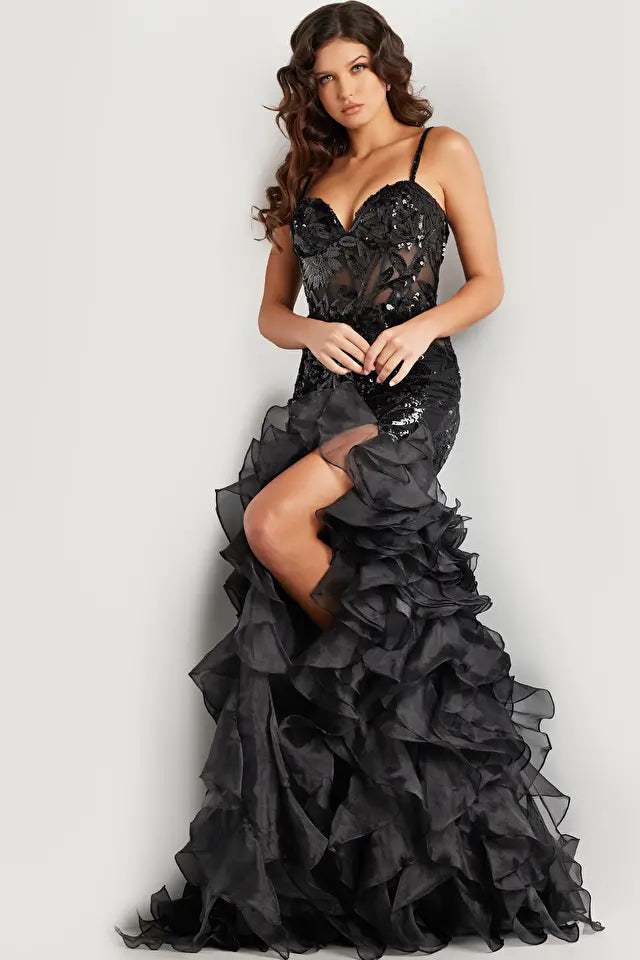 Jovani 38358 Sequin Embellished Mermaid Evening Gown - A glamorous gown featuring an organza ruffle skirt with a slit, sequin embellished bodice with boning and illusion waist, and a mermaid silhouette with a sweetheart neckline. The model is showcasing the dress in black.