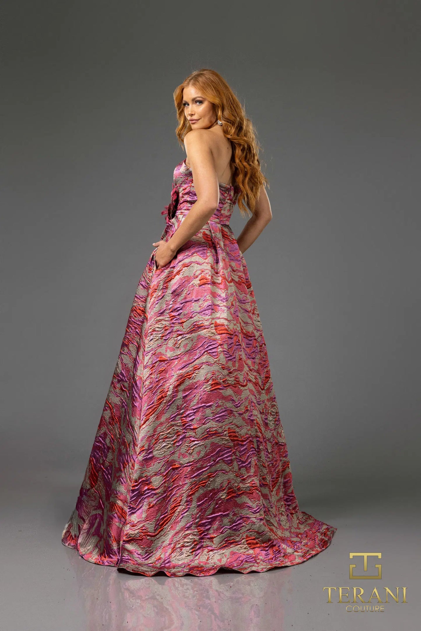 Terani 251E4269 Jacquard Ballgown featuring a strapless design, high slit, and flowing silhouette, perfect for formal evenings and mothers of the bride or groom.  Model is wearing the color fuchsia.