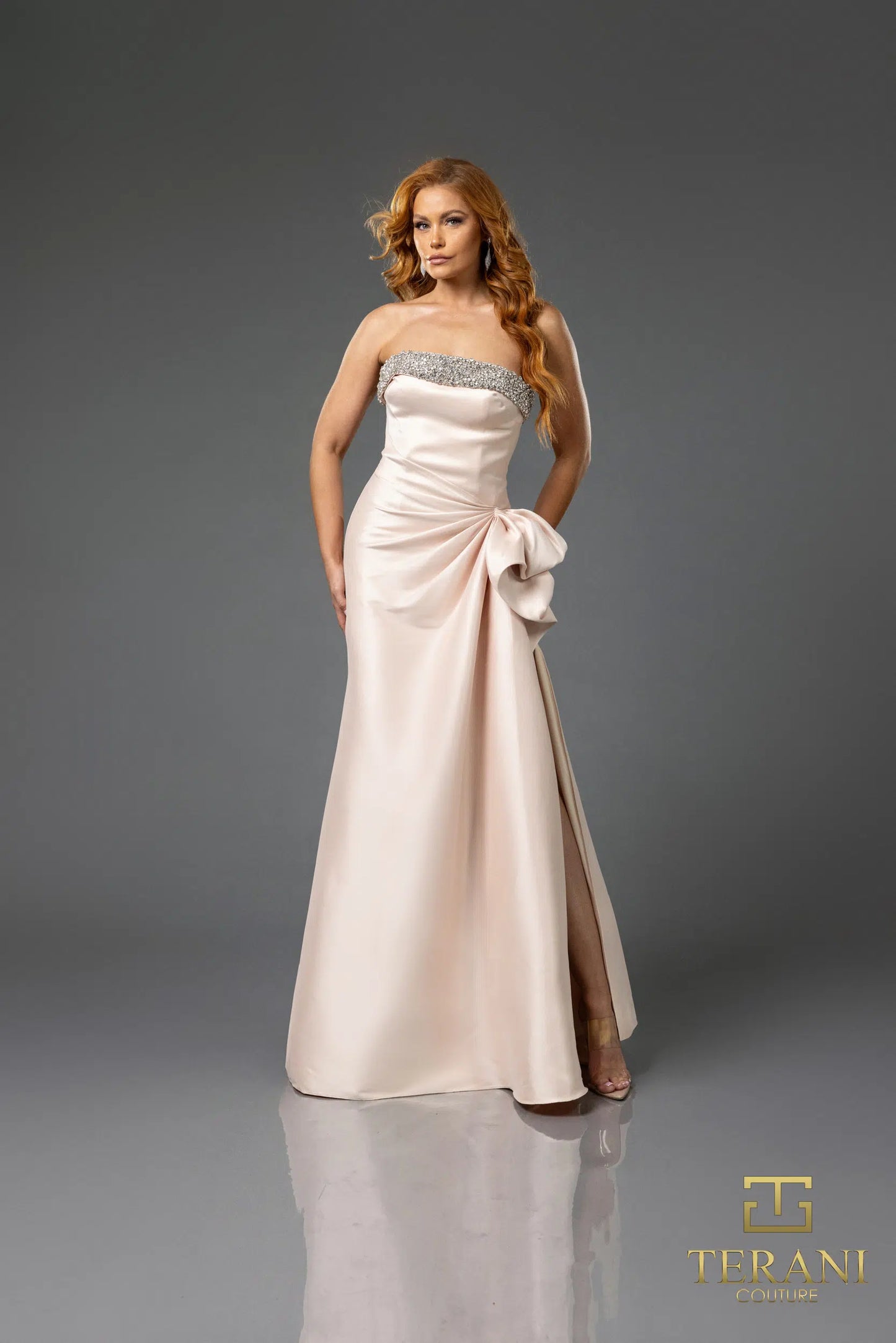 Terani 252E5131 strapless gown with embellished bodice, draped bow detail, and side slit, perfect for formal evenings and mother of the bride or groom.  The model is wearing the dress in the color blush.